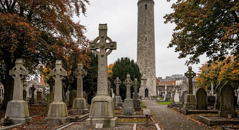 Cimitero di Glasnevin a Dublino con monumentali croci celtiche storiche e la torre circolare sullo sfondo in autunno